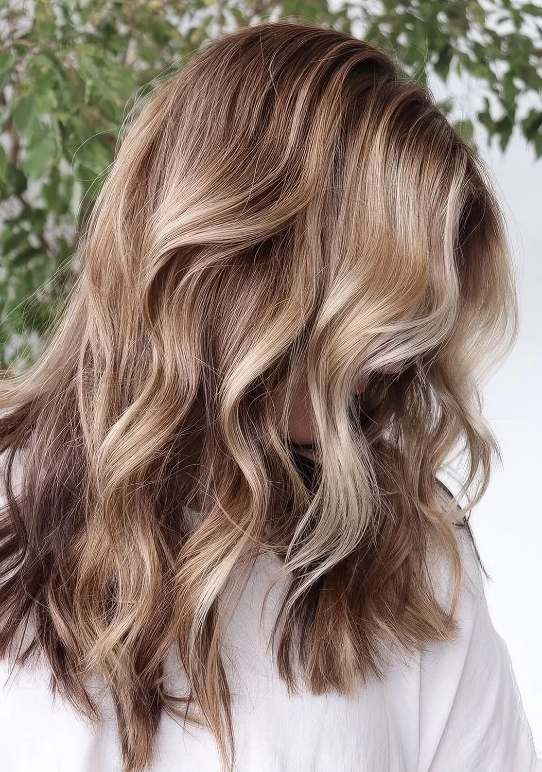 Light brunette hair with blonde balayage and waves.