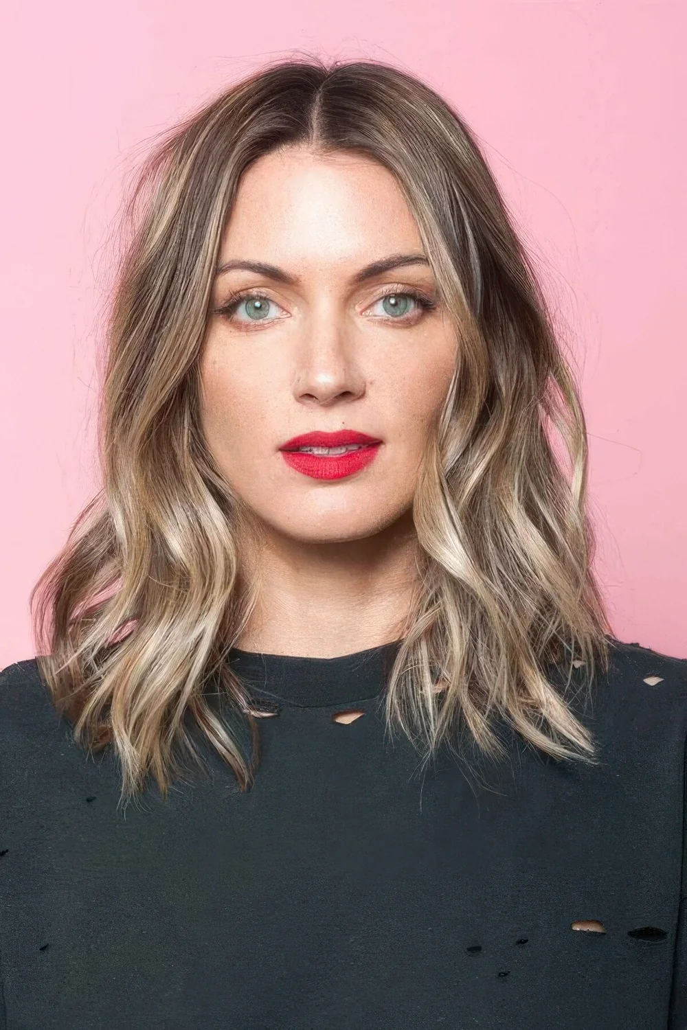 Light brunette medium-length hair with golden blonde balayage and center part plus beach waves.