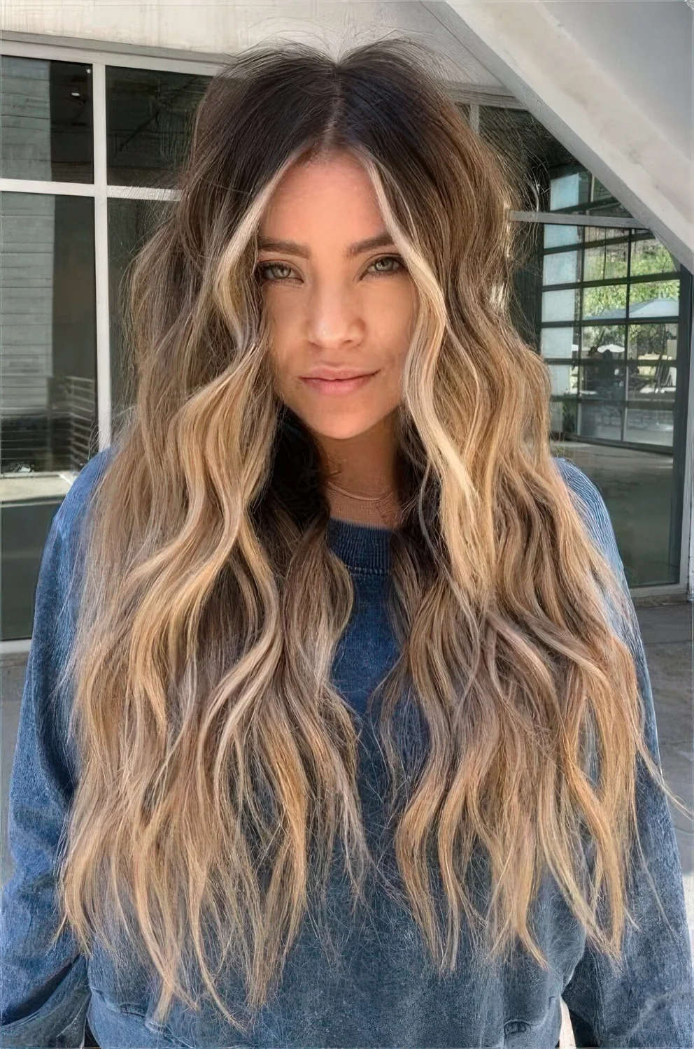 Long bronde hair with a darker root and blonde and caramel balayege plus beach waves.