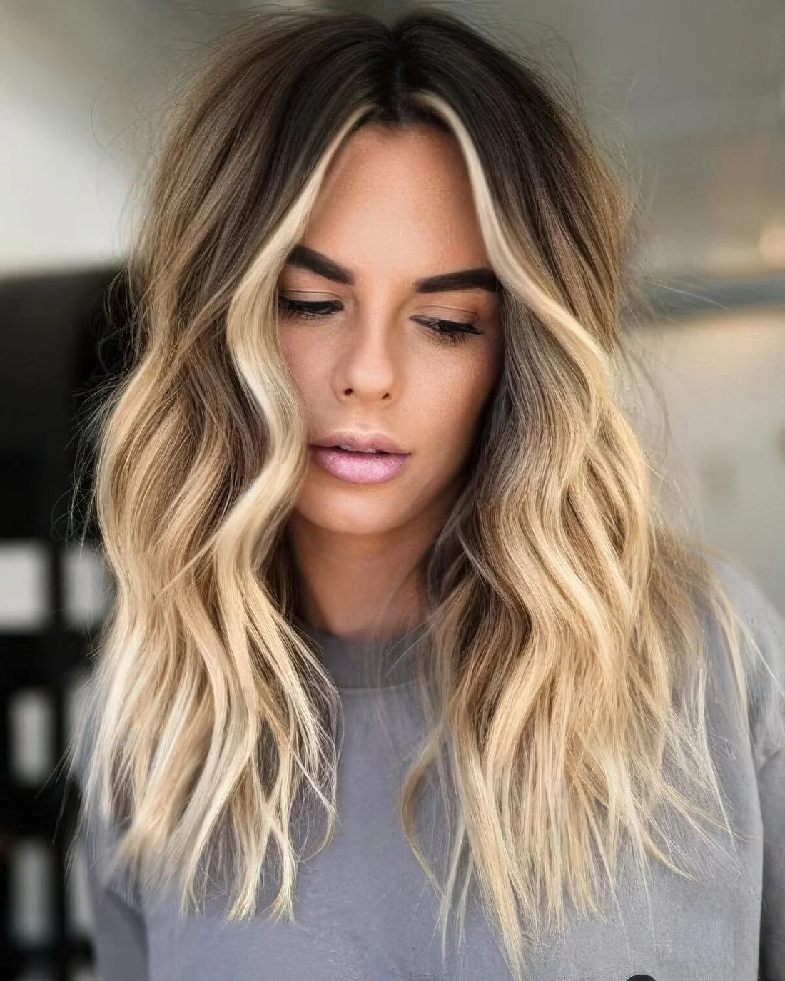 Long brown hair with bright blonde balayage and a money piece plus beachy waves.