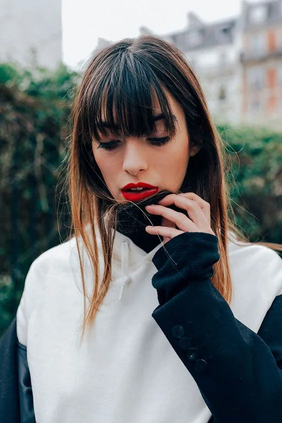 Long straight brown hair with classic wispy Birkin bangs.