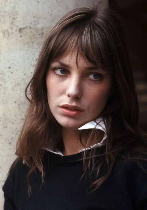 Famous Jane Birkin wearing brown shoulder-length hair and wispy bangs with parting that.
