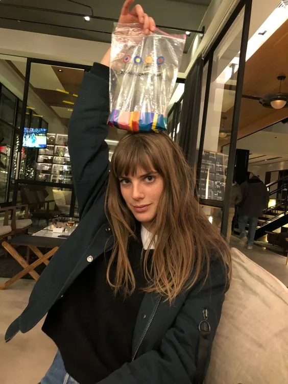Long messy brown hair with lighter chestnut balayage and classic Birkin bangs.