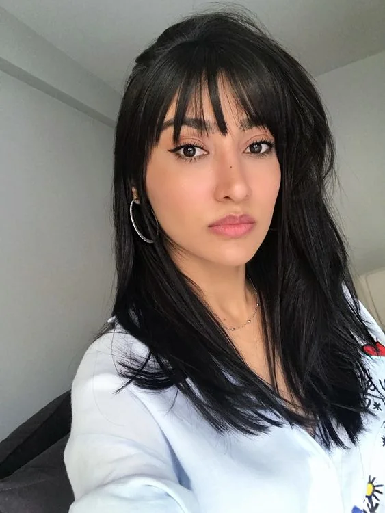 Long straight black hair with wispy Birkin bangs.