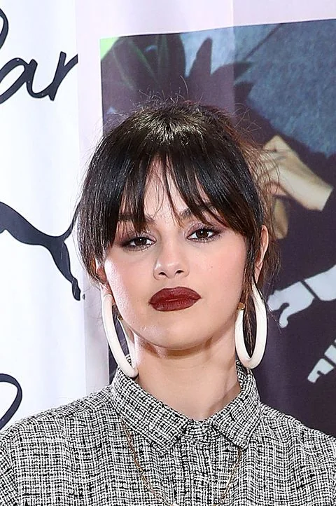 Selena Gomez wearing an updo with wispy Birkin bangs with parting in the middle.