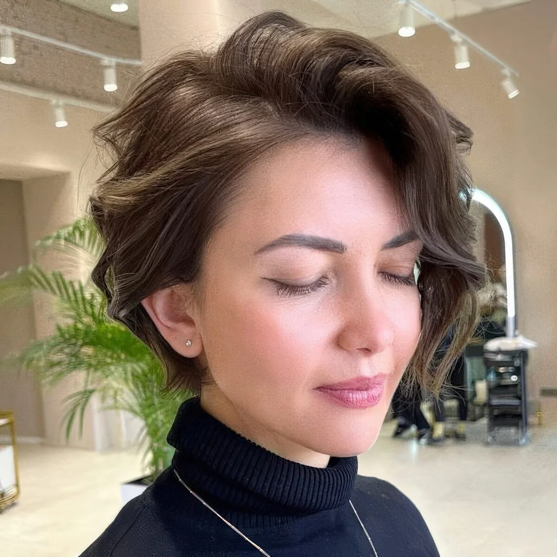 Wavy brown bixie with a lot of volumem and side bangs.
