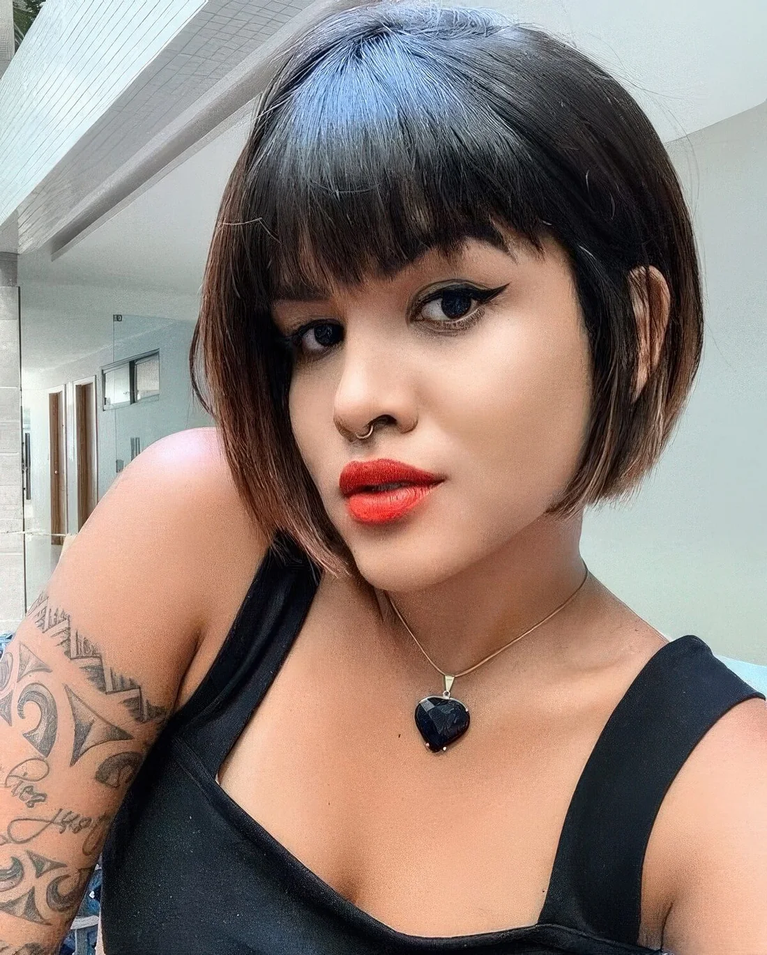 Black jaw-length bob with caramel balayage and blunt bangs.