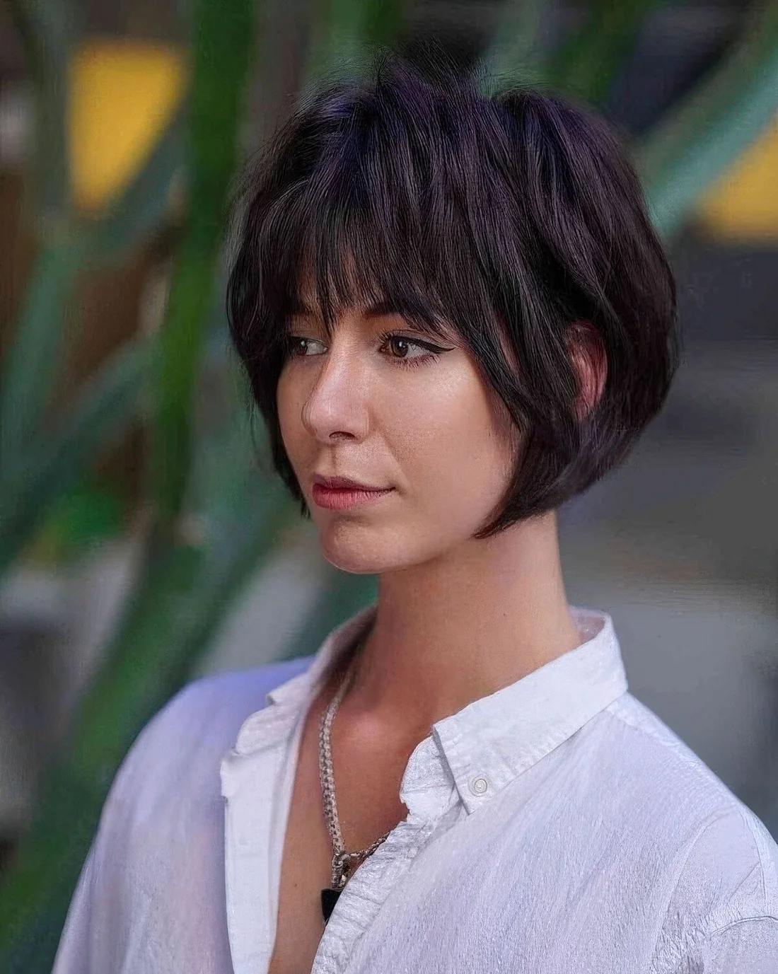 Black layered jaw-length bob with wispy bangs and shaggy layers.