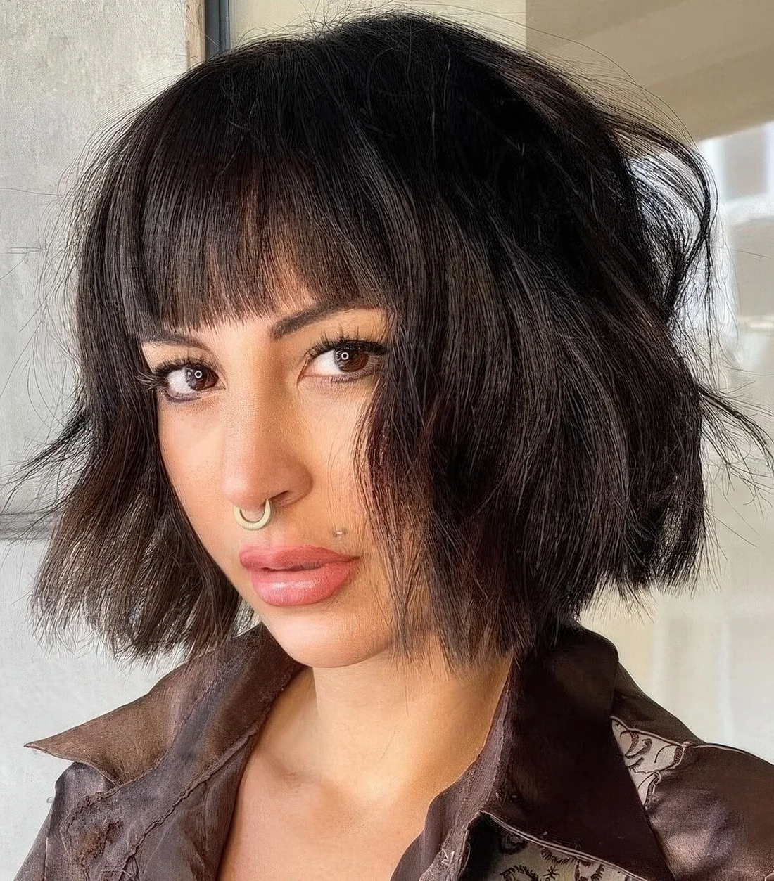 Black textural and wavy chin-length bob with waves and blunt bangs.