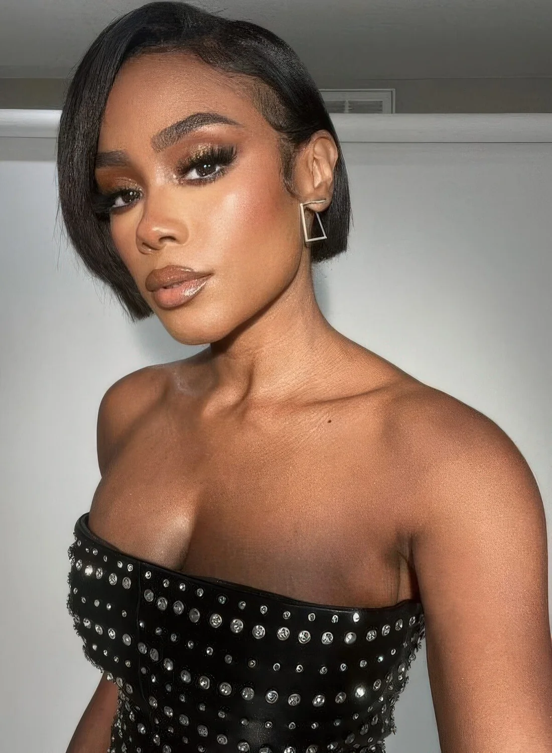 Short black bob with side part and a shiny finish.