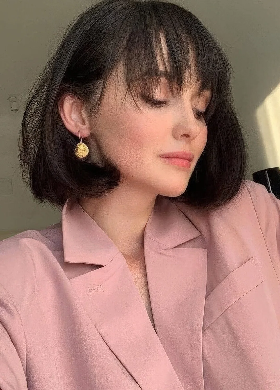 Medium black bob with rounded ends and wispy bangs that accent the eyes and the face.