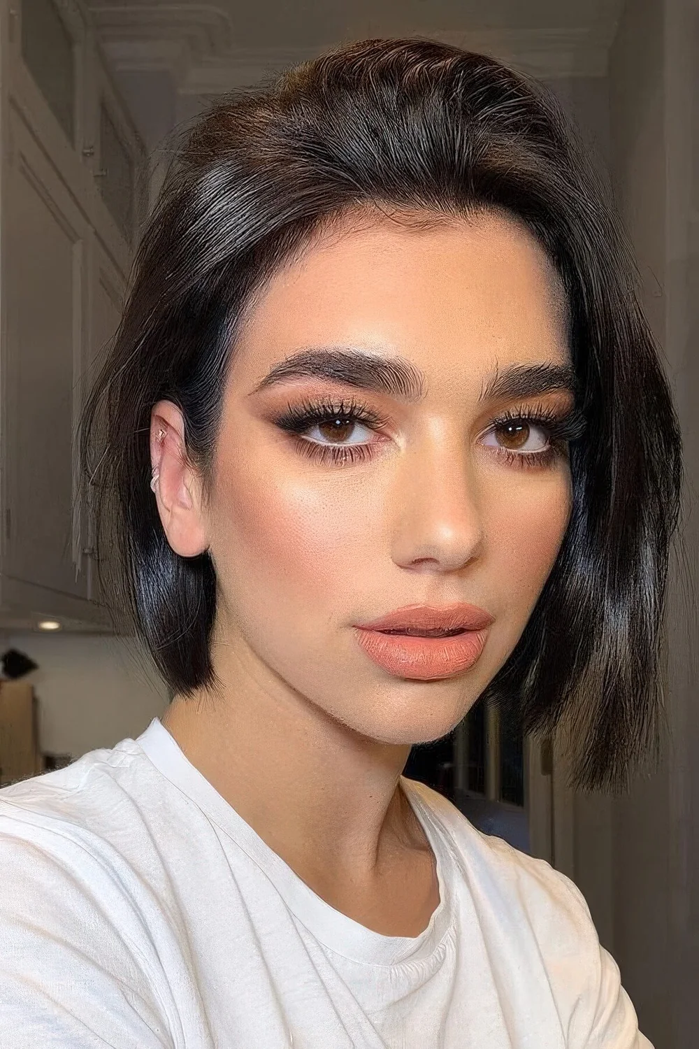 Dua Lipa rocking a chin-length black bob with a shiny finish.