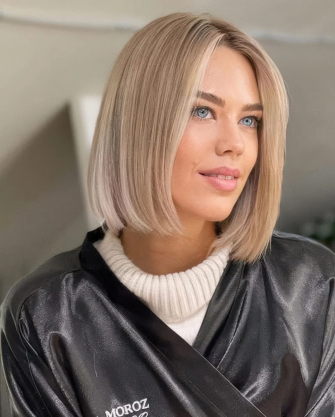 Blonde blunt midi bob with a soft blonde shade and middle part.