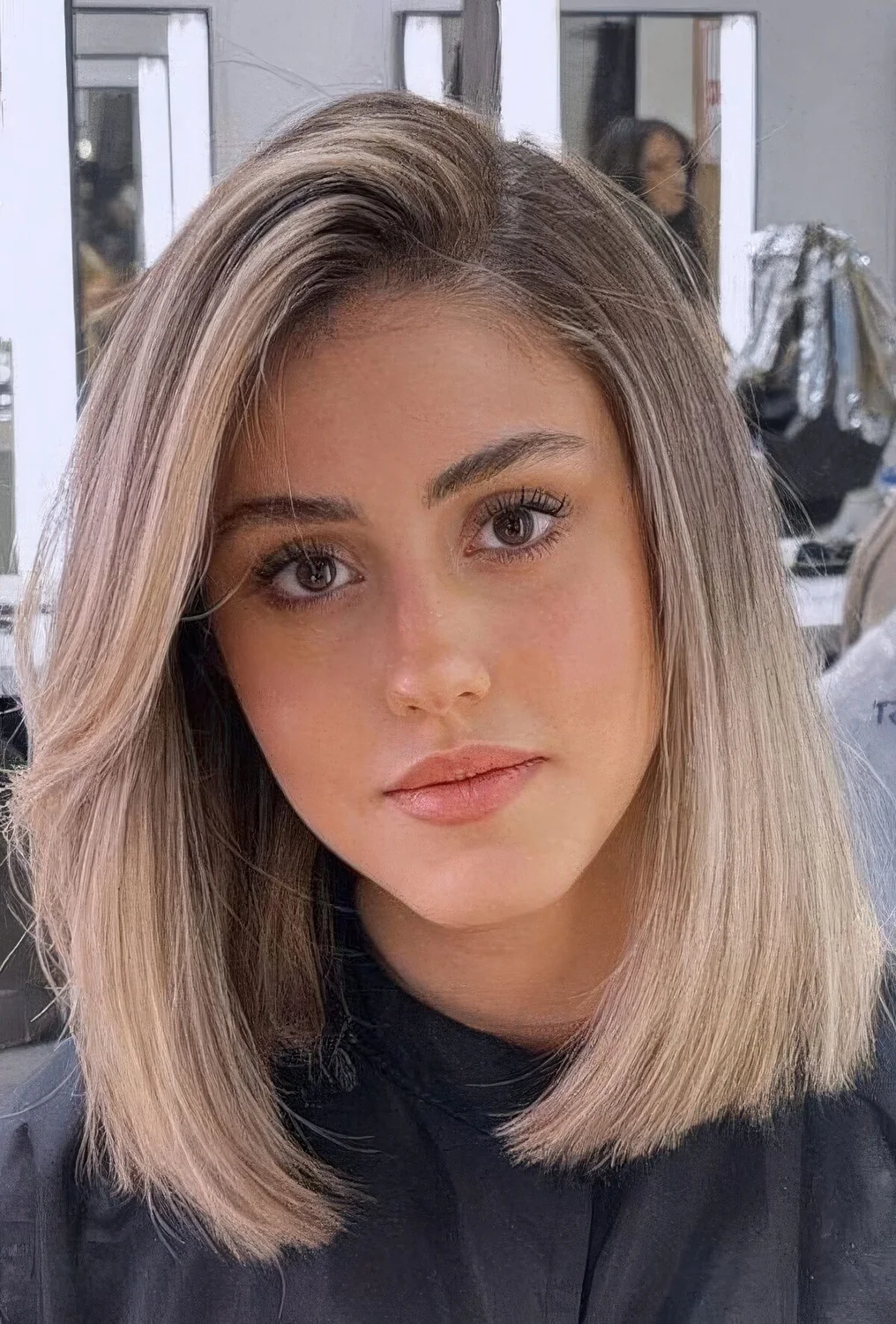 Blonde long bob with a darker root and curved ends.