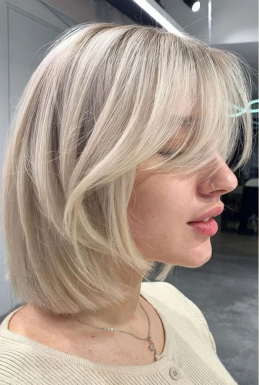 Chic icy blonde long bob with curtain bangs.