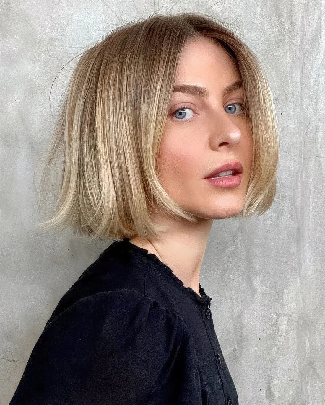 Chin-length blonde bob with a darker root.