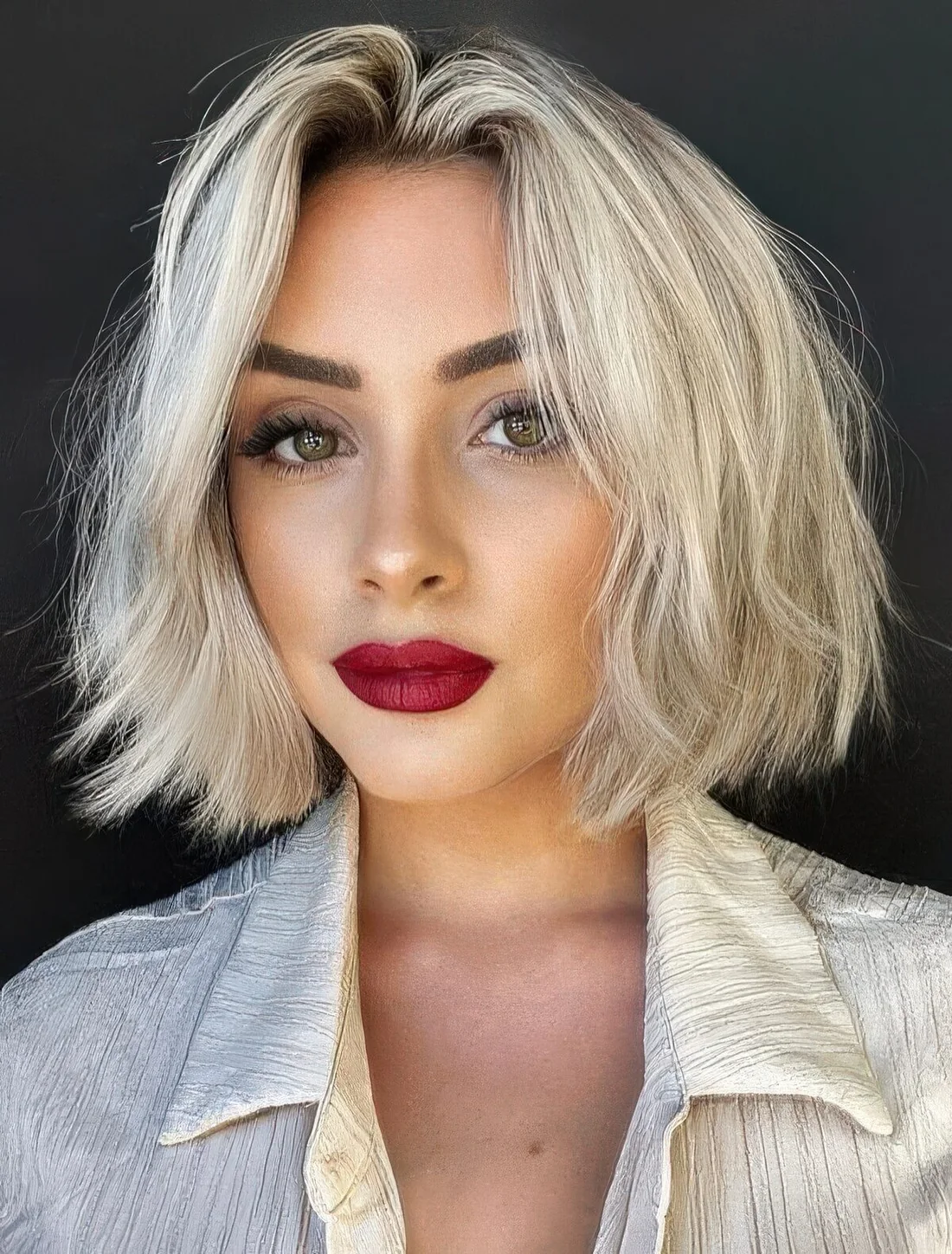 Chin-length icy blonde bob with a darker root and a lot of volume.
