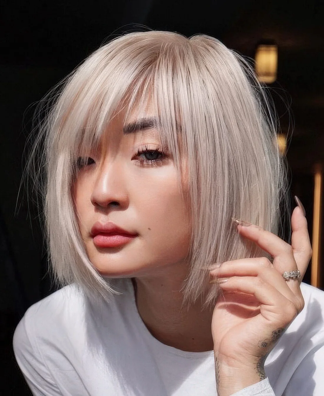 Chin-length platinum blonde bob with wispy bangs and side part.
