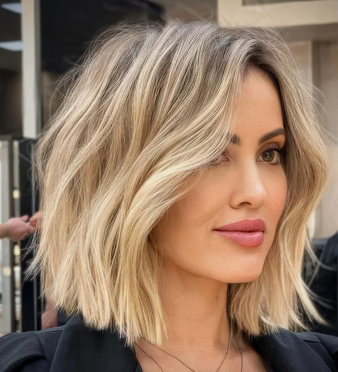 Long blonde bob with a darker root and messy waves.