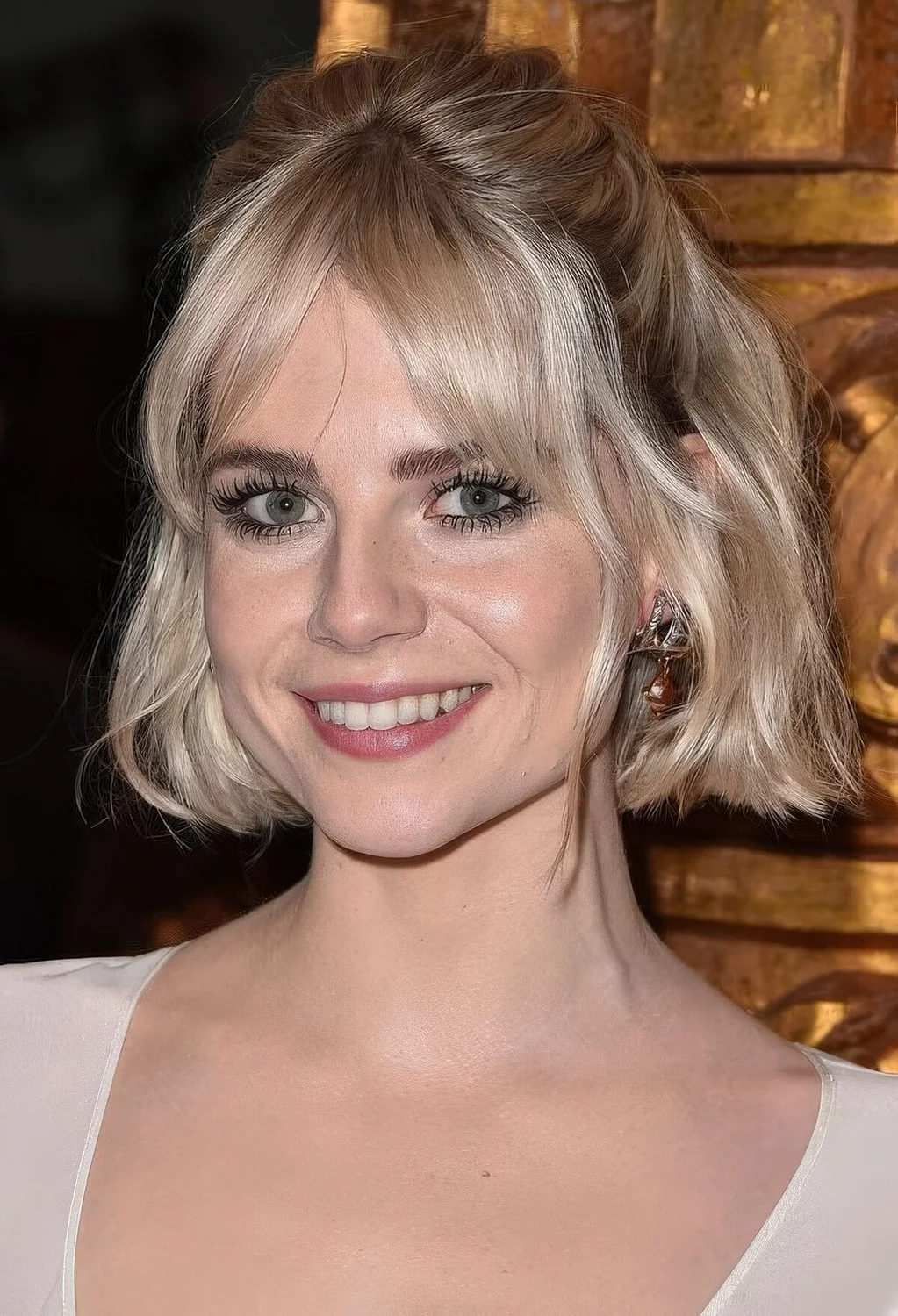 Platinum blonde chin-length bob with curtain bangs and waves styled as a half updo.