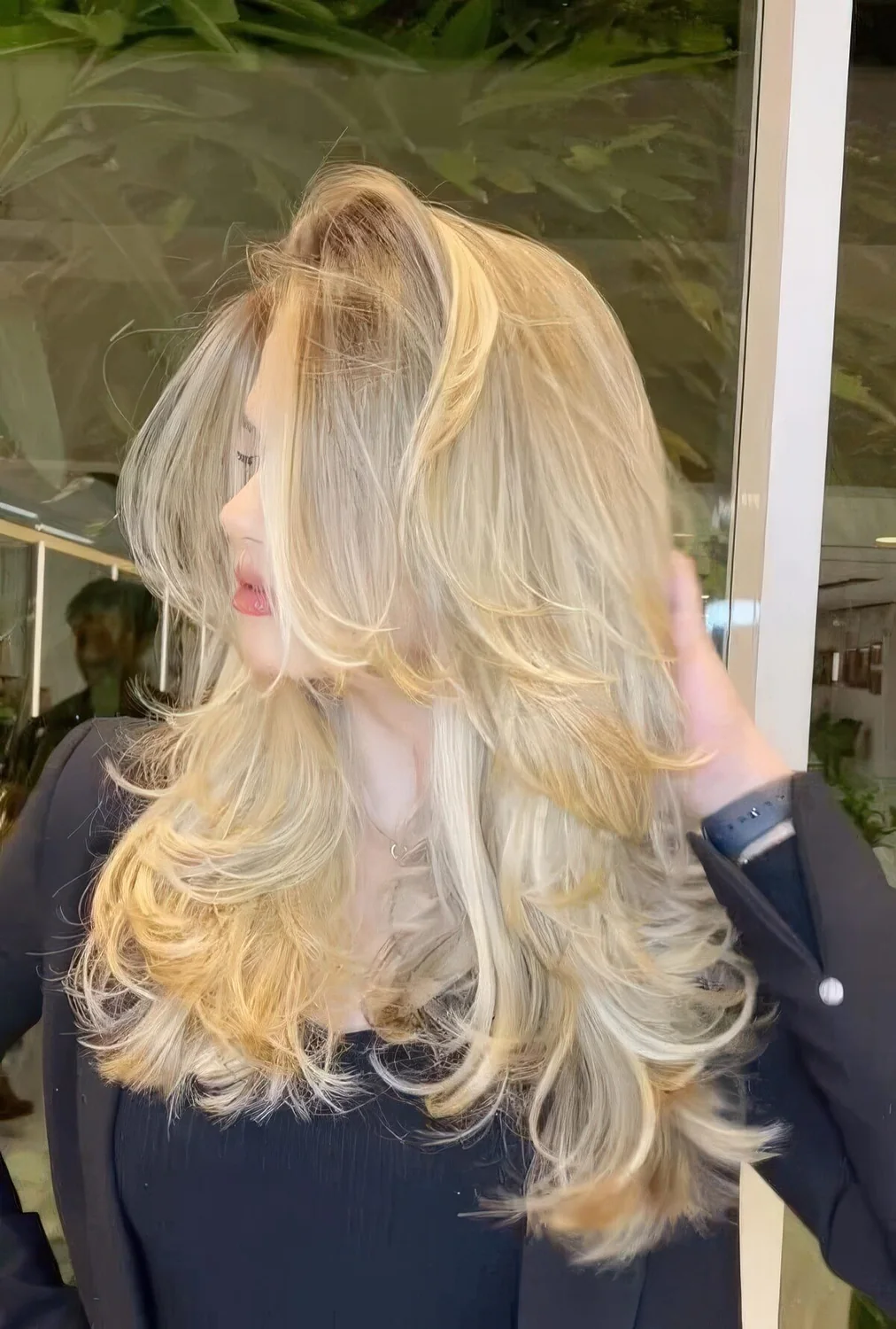 Creamy blonde butterfly haircut with wavy ends and a lot of volume.