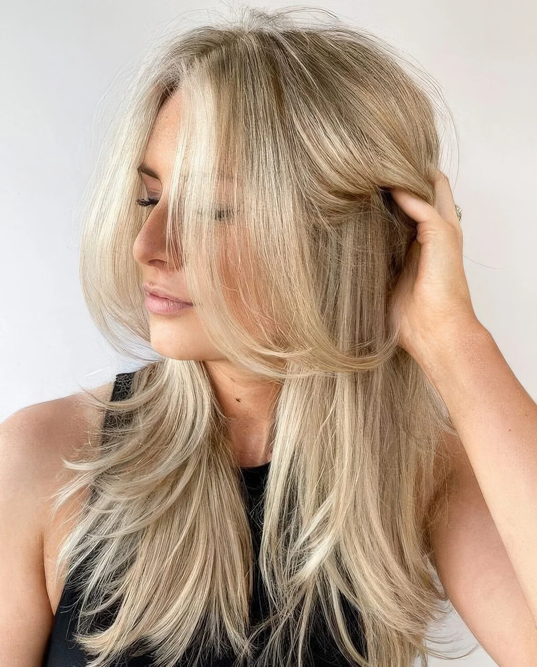 Bleached blonde butterfly haircut with curled ends and a bit of volume.