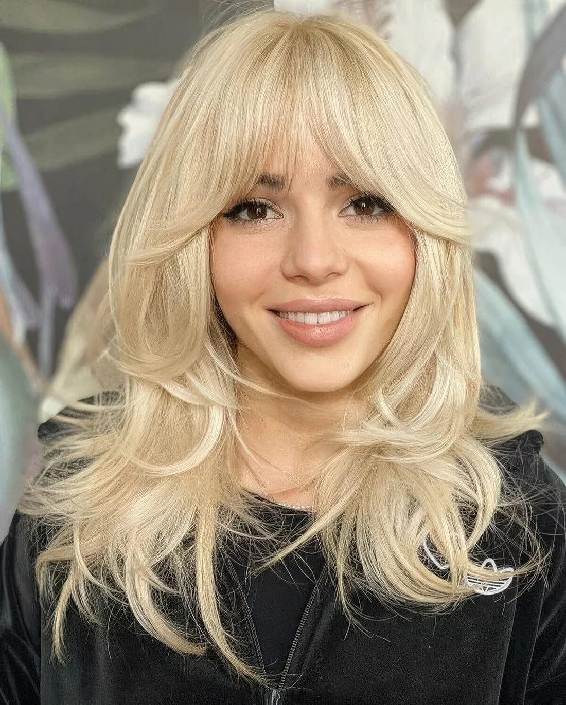 Bleached butterfly haircut on medium-length hair, with some messy volume and bottleneck bangs.