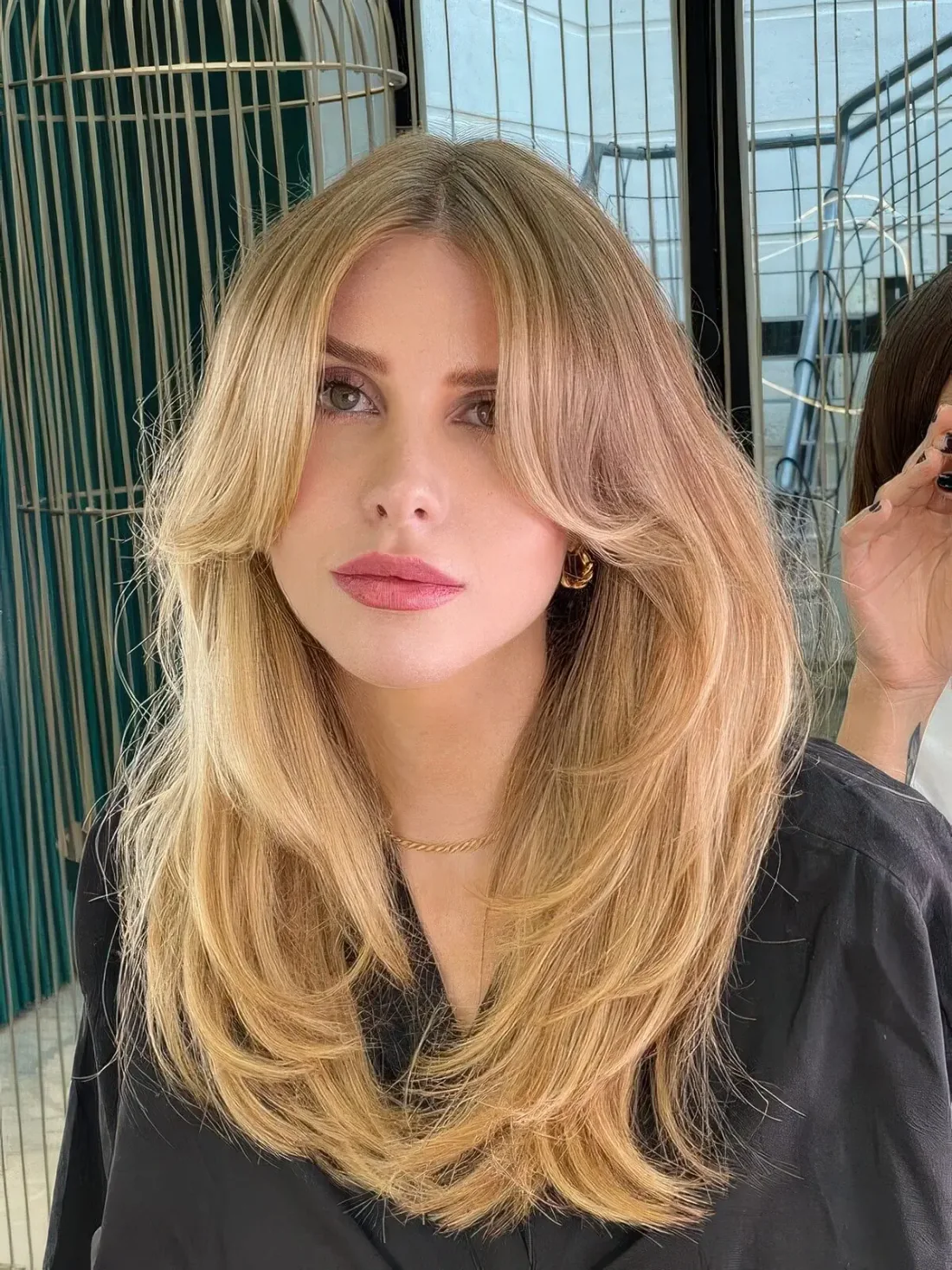 Fab blonde butterfly haircut with a darker root, curtain bangs and some ends curved.