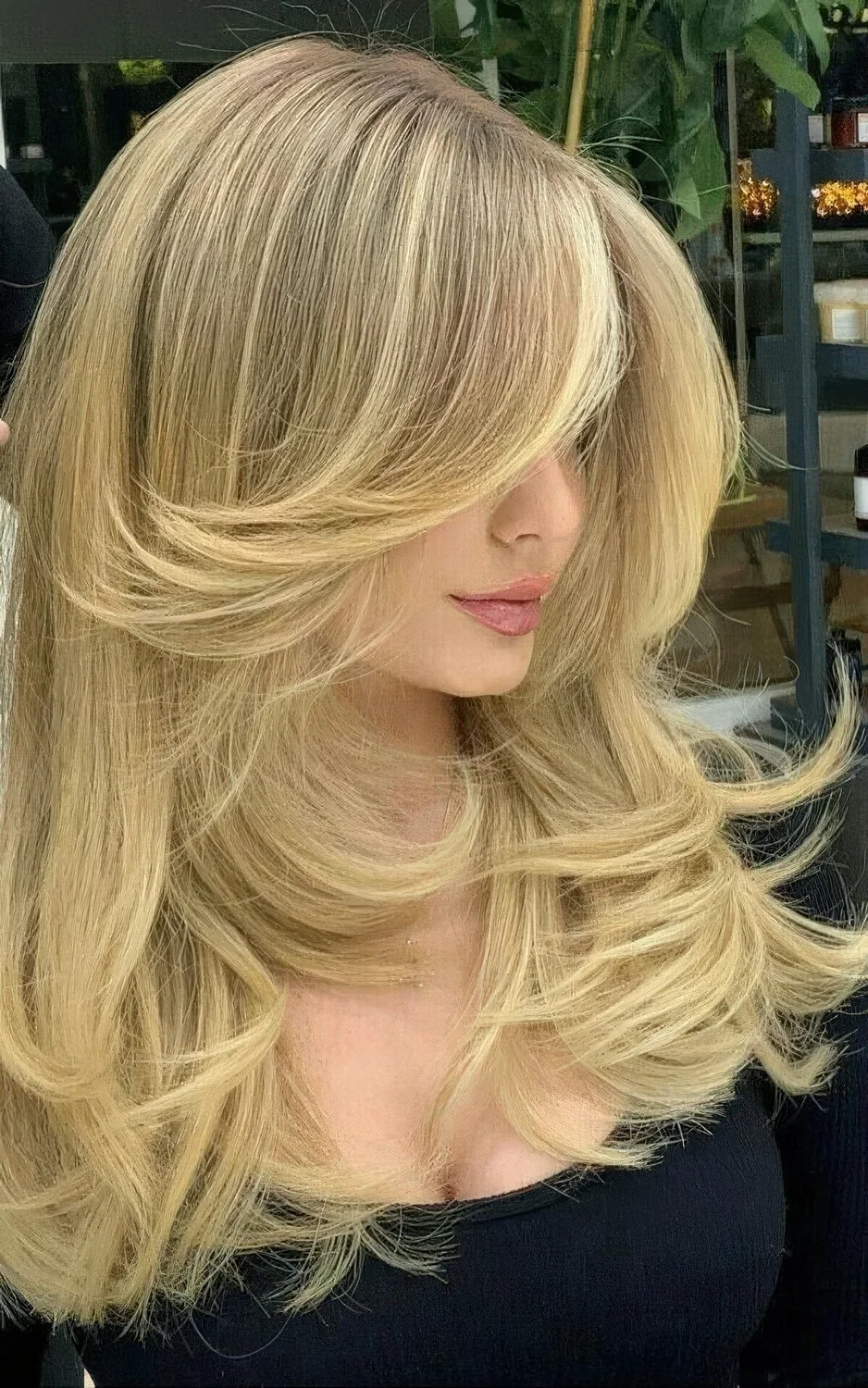 Golden blonde butterfly haircut with wavy ends and a lot of volume.
