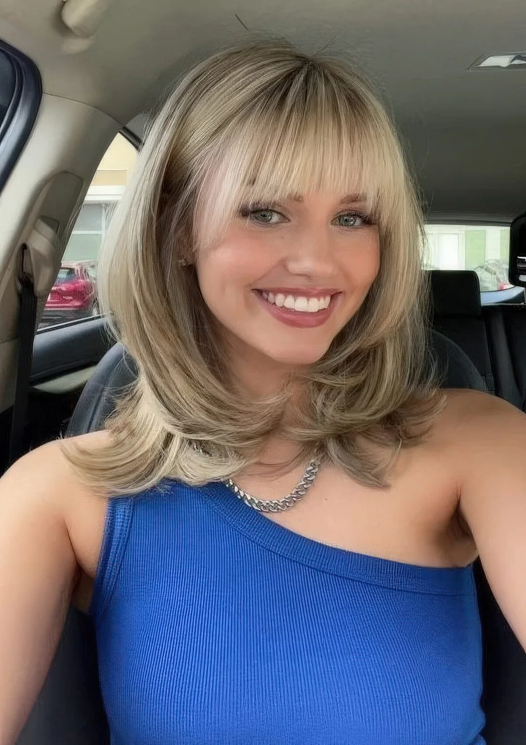 Medium blonde butterfly haircut with blunt bangs and curved ends.