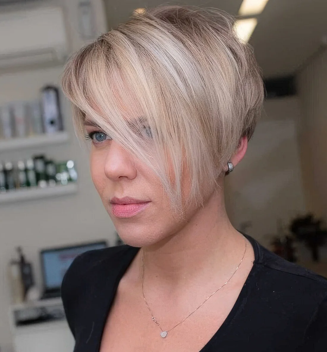 Blonde pixie haircut with icy highlights and long side bangs that.