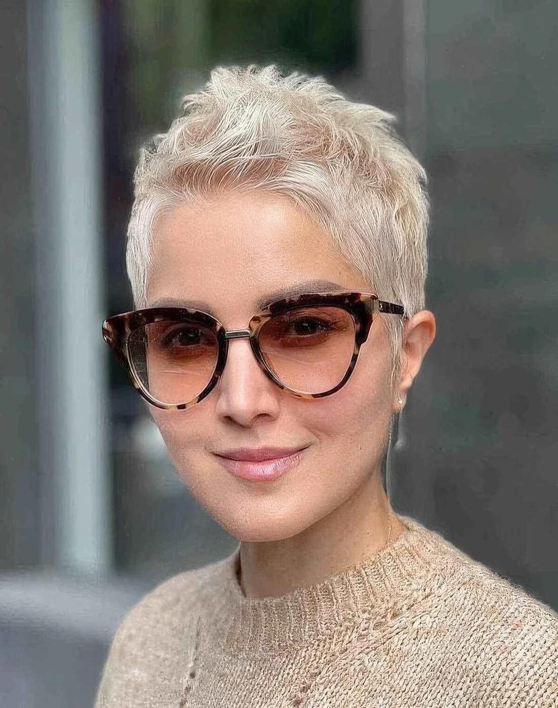 Creamy blonde pixie cut with styling on the top.