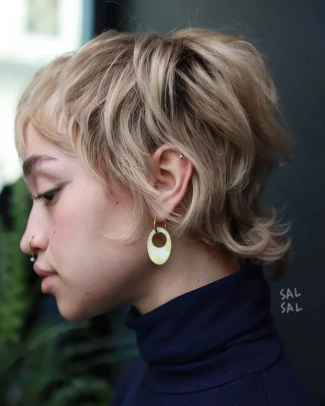 Blonde layered pixie with natural curls and a texture, with darker root and long sides and fringe.