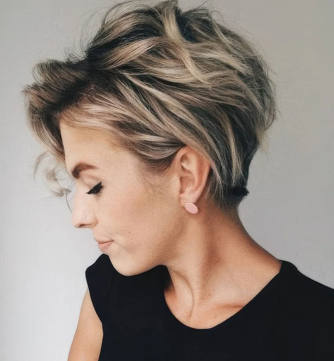 Long pixie with blonde balayage and a darker root.