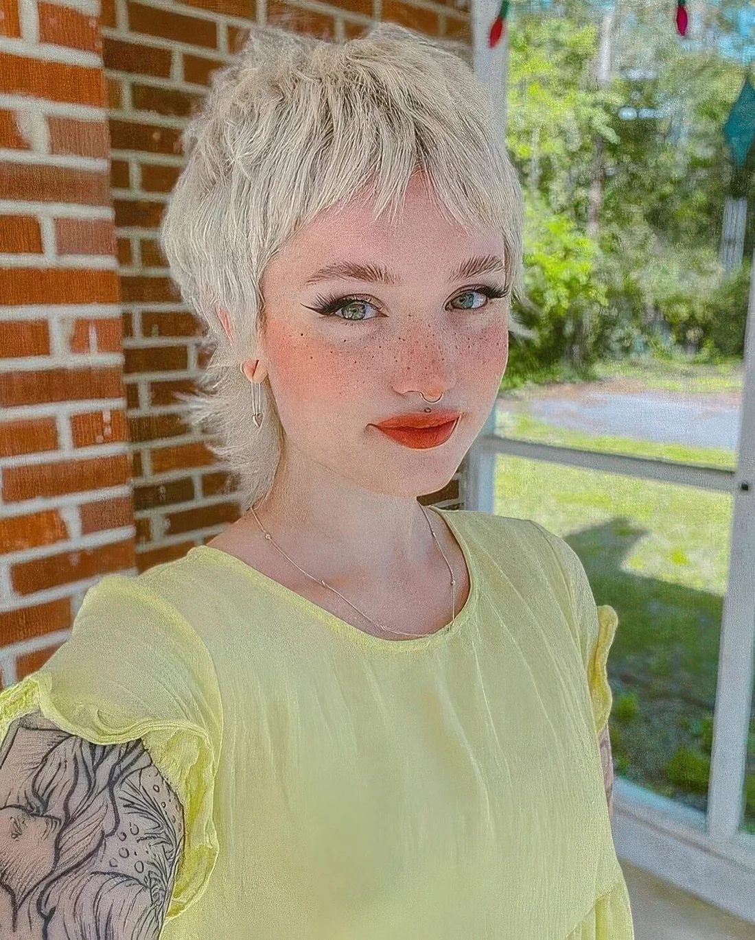 Short blonde mullet with bangs and a lot of dimension plus curled ends.