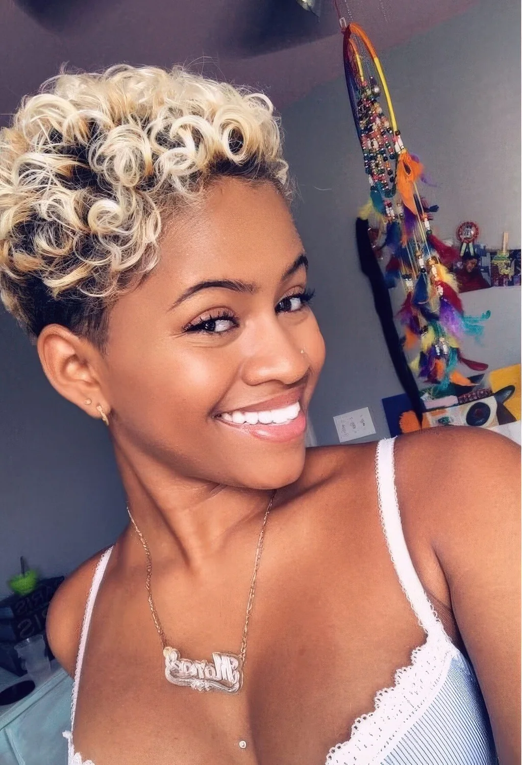 Curly pixie haircut with natural blonde and a dark root for a cute and girlish look.