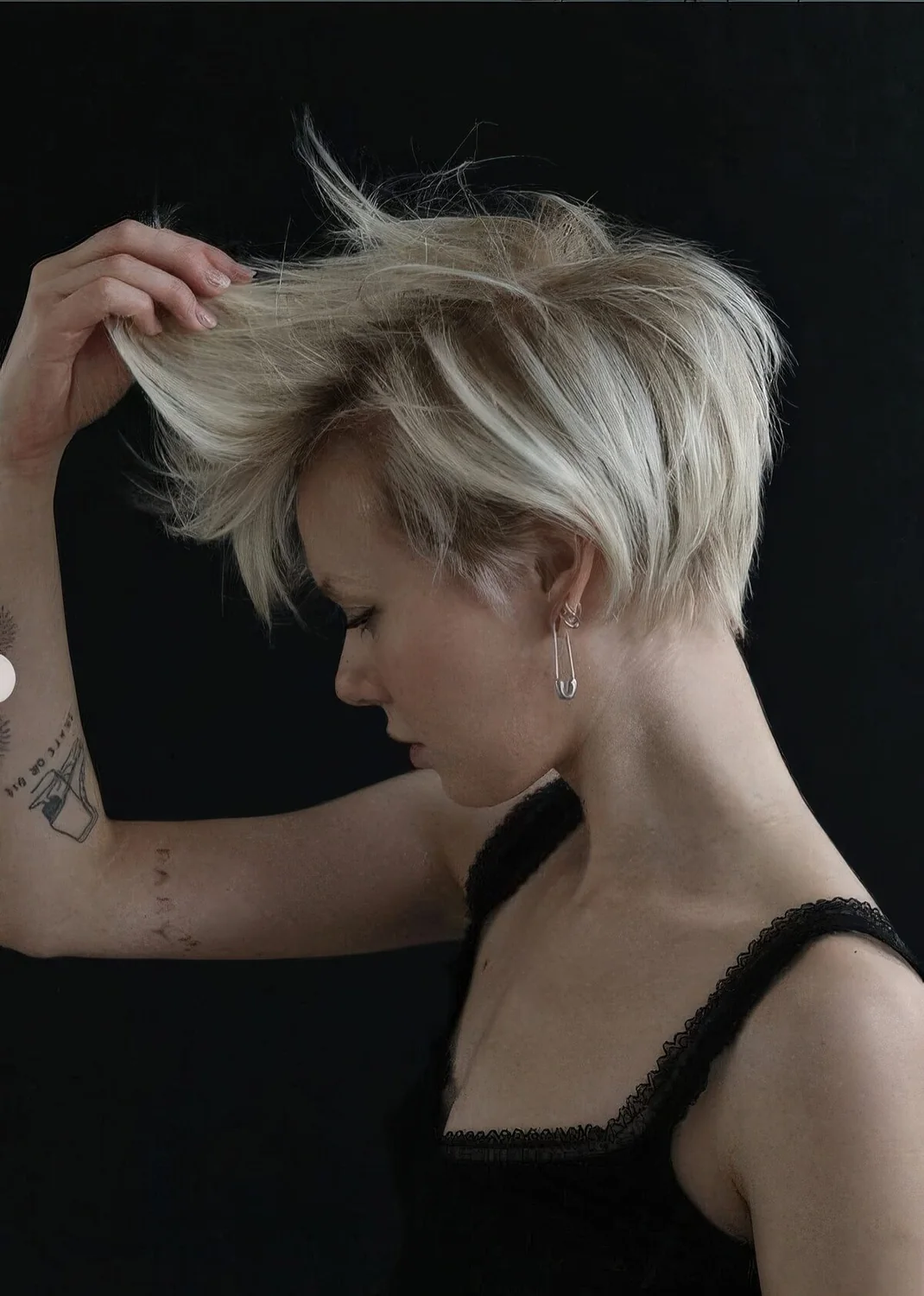 Long pixie with side part, straight textured hair and curled ends plus a lot of volume.