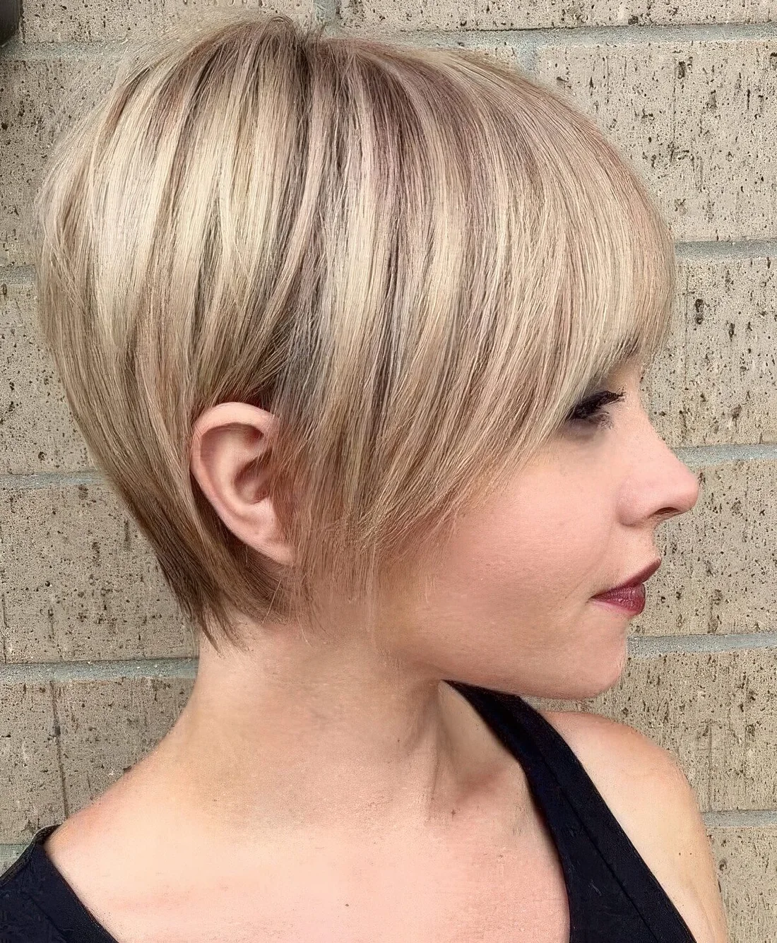 Longer pixie haircut with sleek styling and a light blondie balayage.