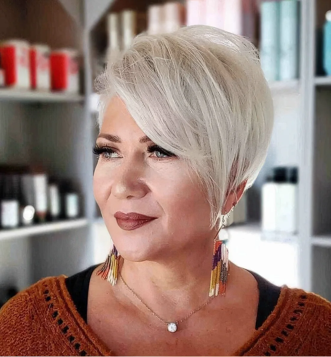 Icy blonde pixie haircut with long side bangs, layers and texture.