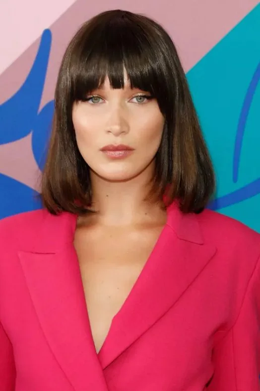 Bella Hadid wearing a shoulder-length dark brown bob with blunt bangs.