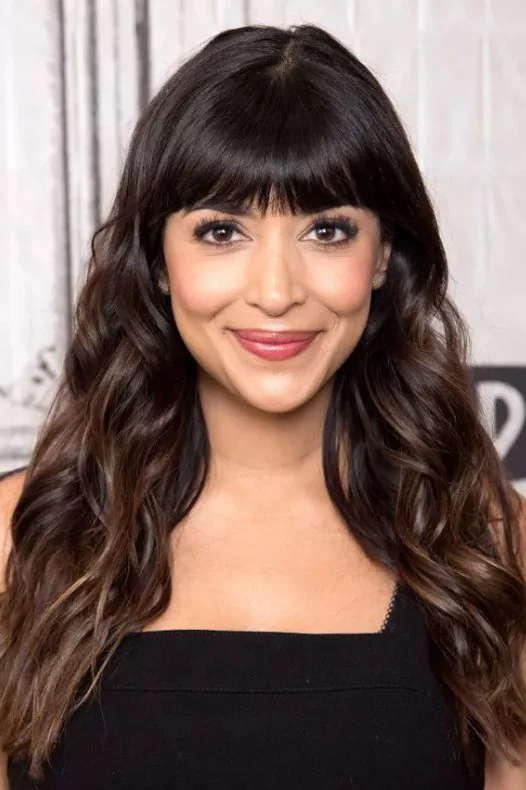 Hannah Simone's straight across blunt bangs with her long hair highlights the structure in her heart shaped face.