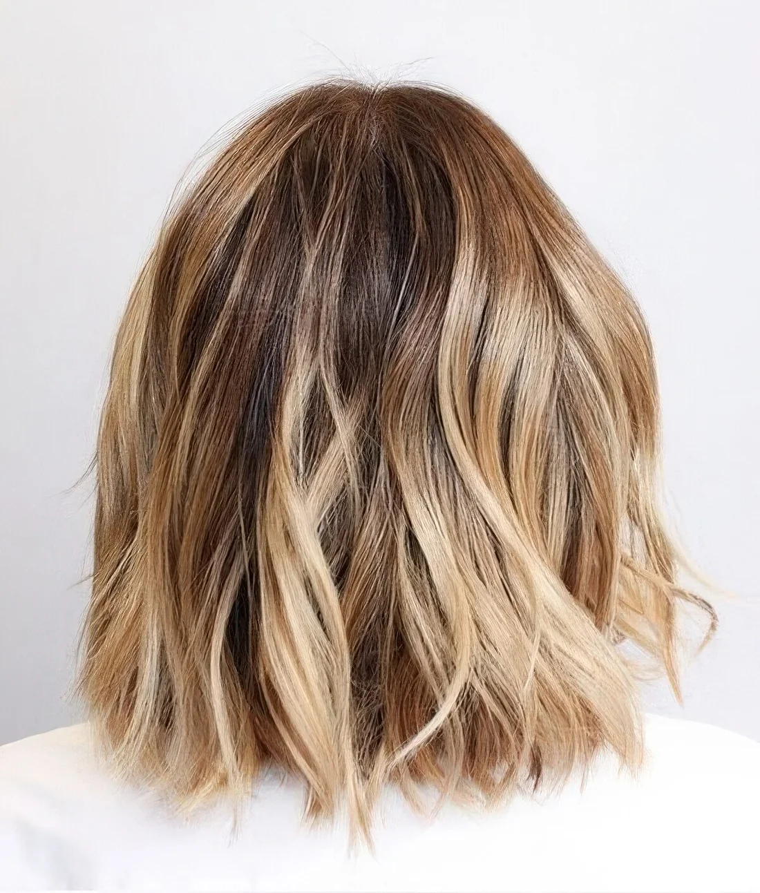 Bit messy long bronde bob with golden and bleached blonde balayage and a darker root.