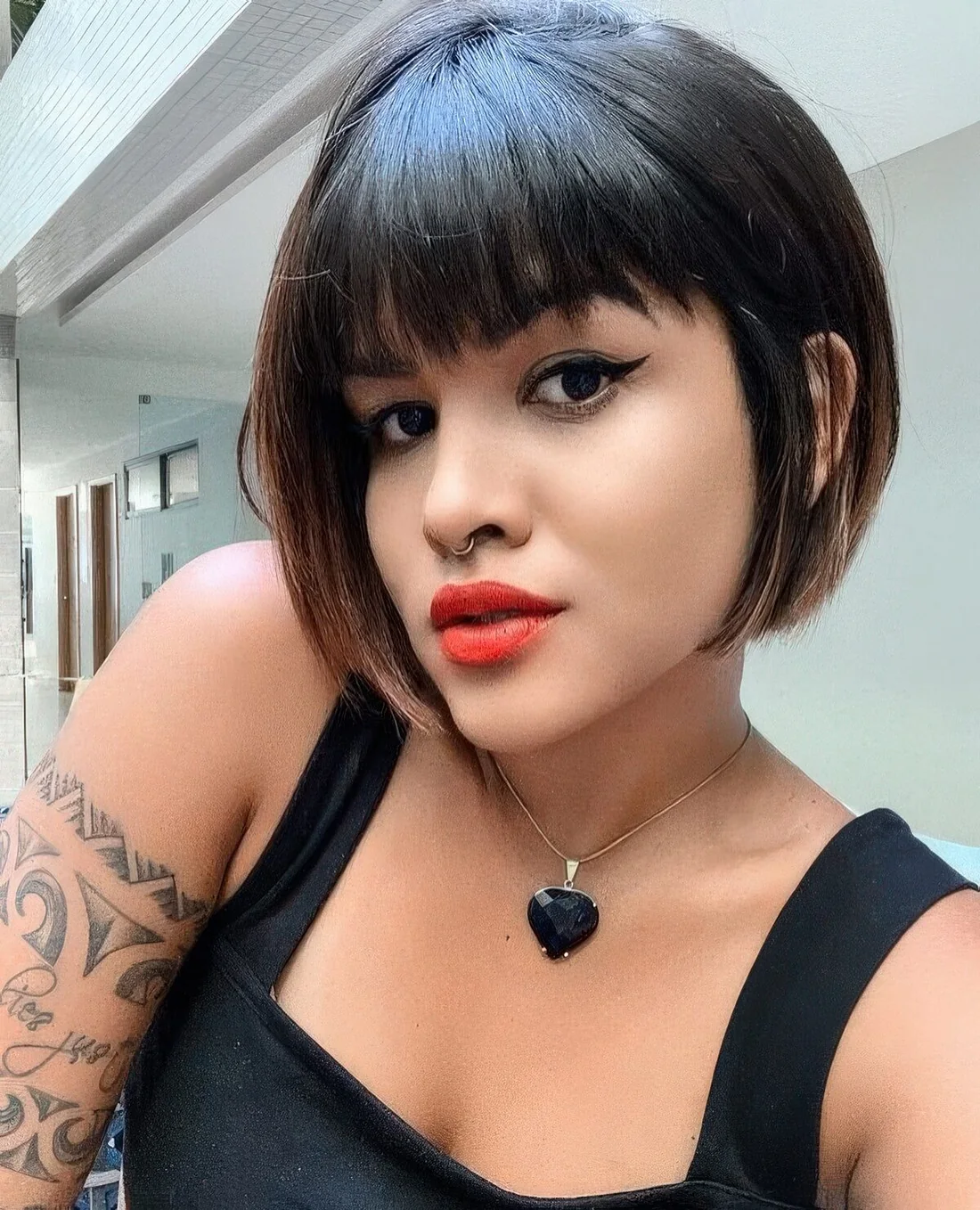 Black jaw-length bob with caramel balayage and blunt bangs.