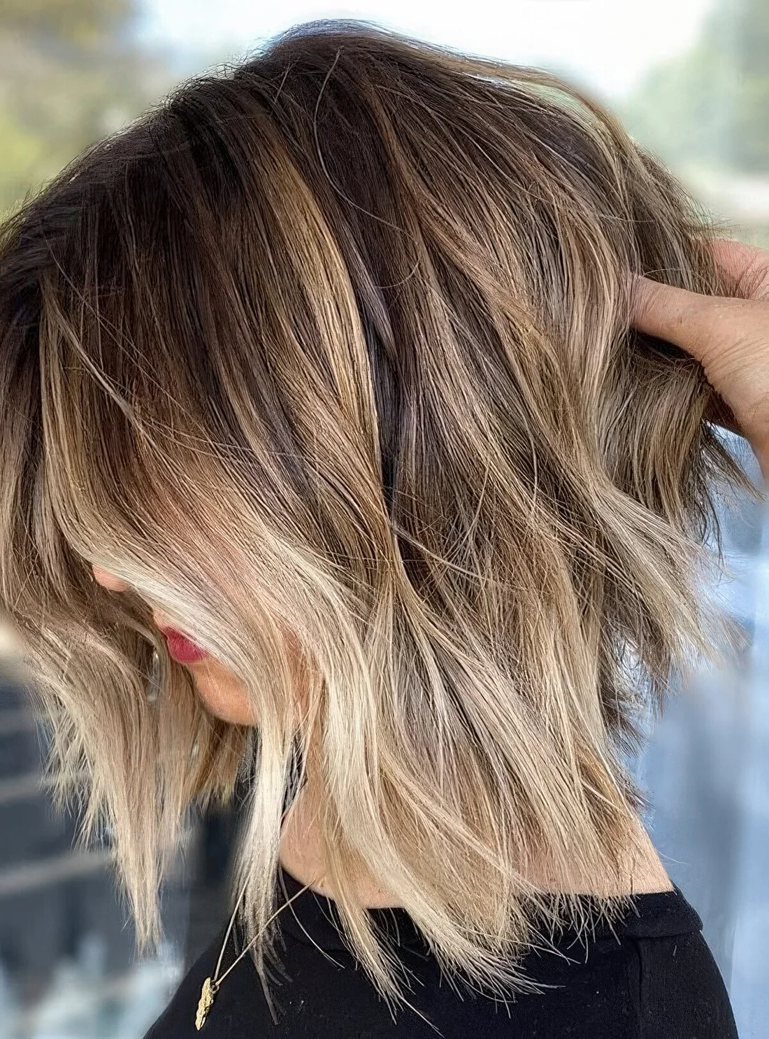 Brown bob wih blonde balayage, with messy waves and bangs.
