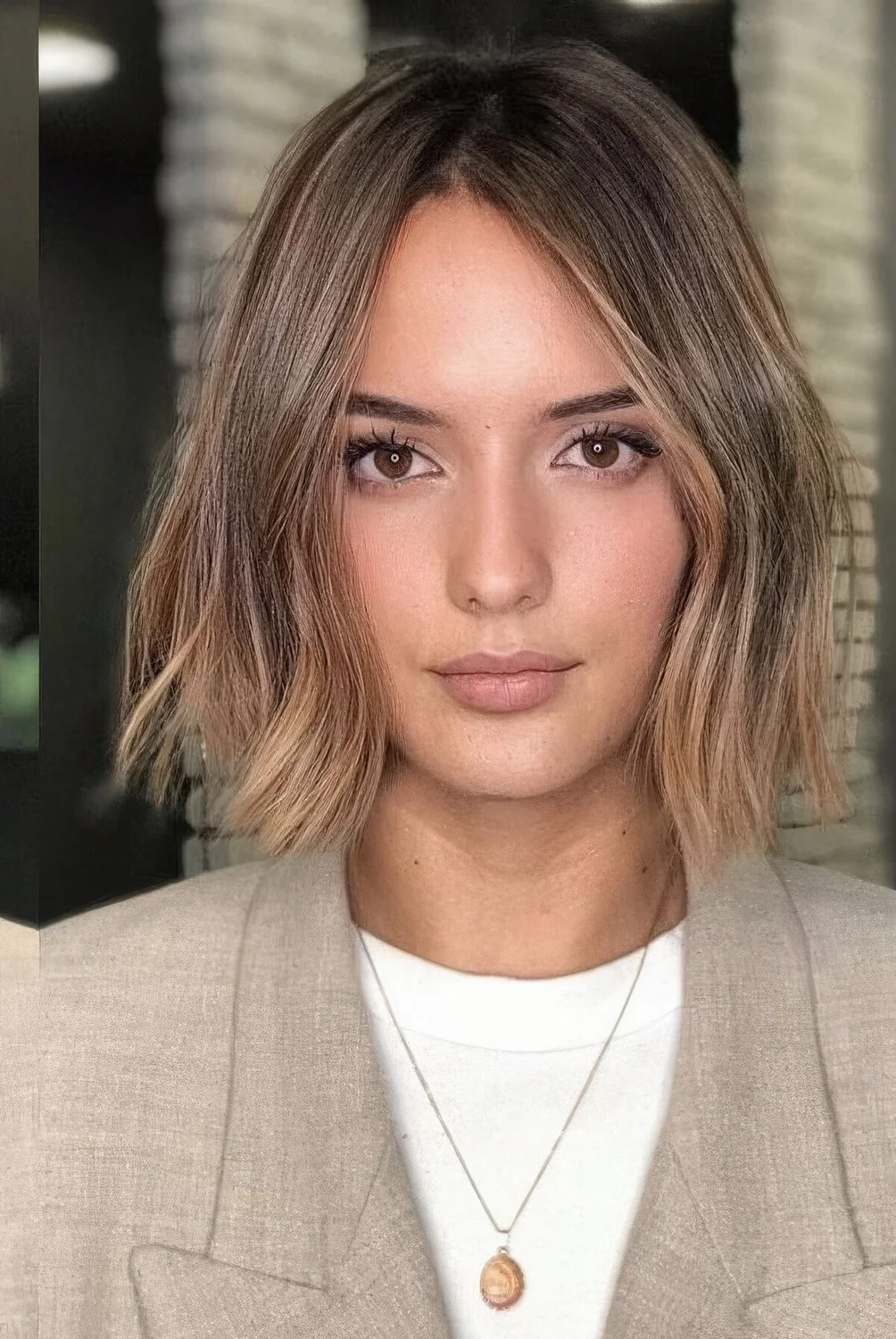 Brown bob with darker root and caramel and gold balayage, with irregular parting and slight waves.