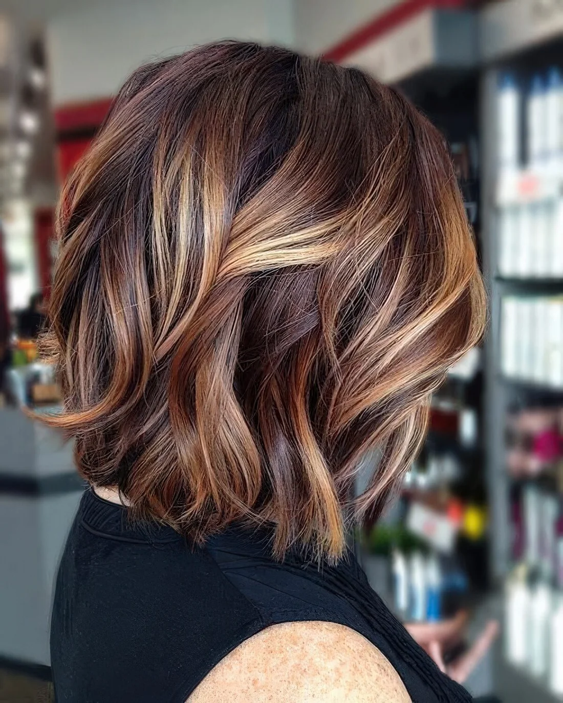 Chic and bold long bob in auburn and brown, with honey blonde balayage and waves.