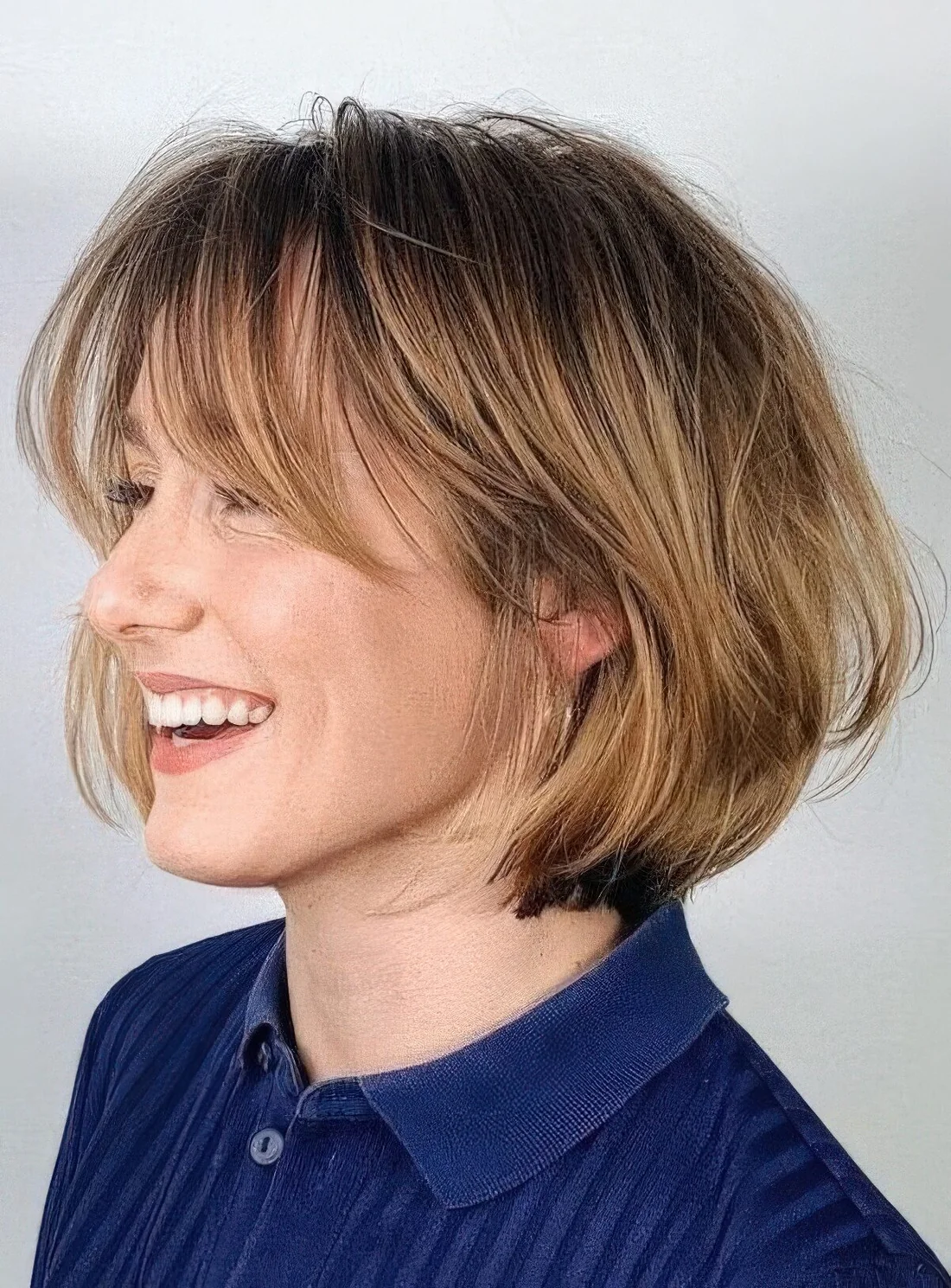 Chin-length bob with honey blonde balayage and long curtain bangs, curved ends and a bit of volume.