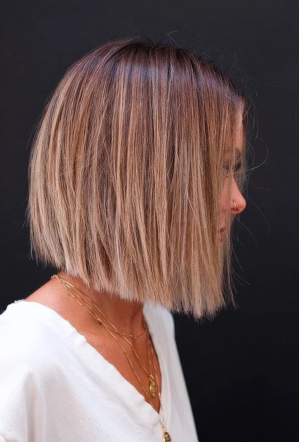 Cihc blunt bob with a brown root and blonde balayage.