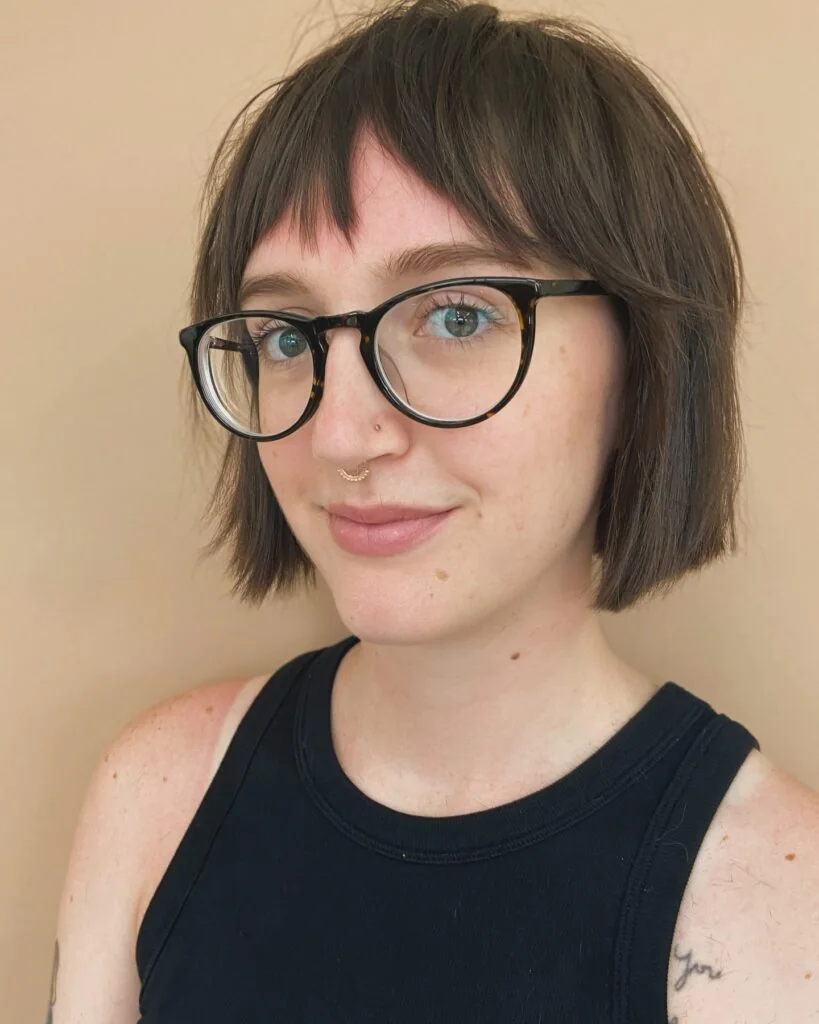 Brunette jaw-length bob with micro bangs and glasses.
