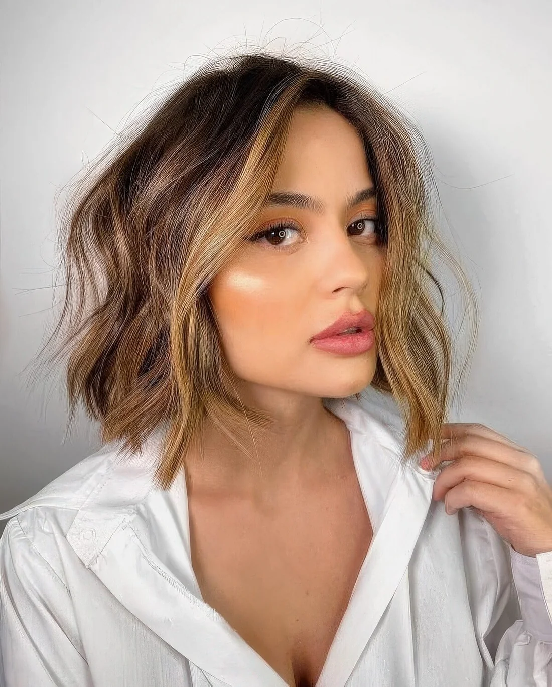 Brown bob with blonde balayage and face-framing locks, with messy texture.